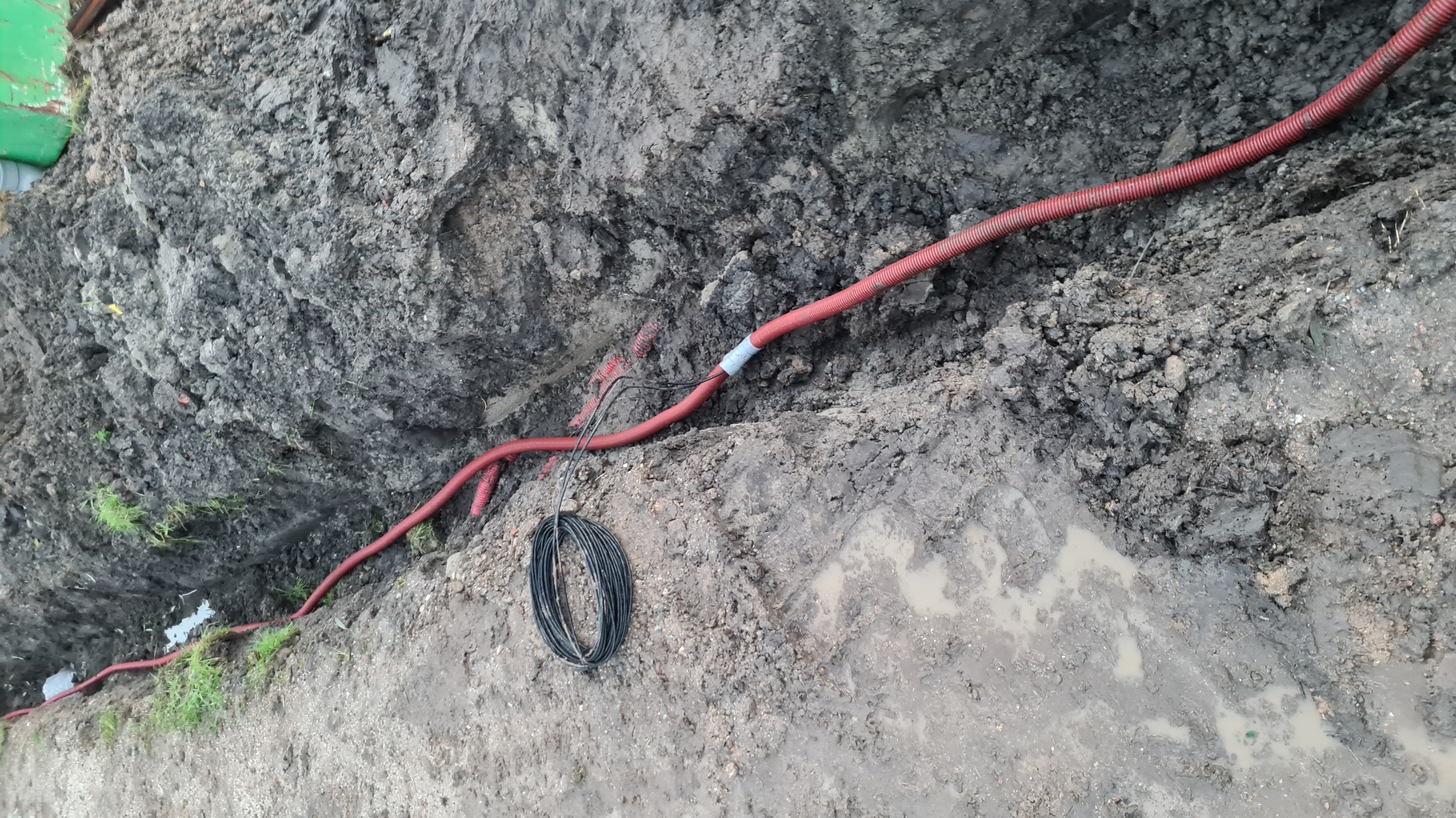 Rode mantelbuis in sleuf met modder